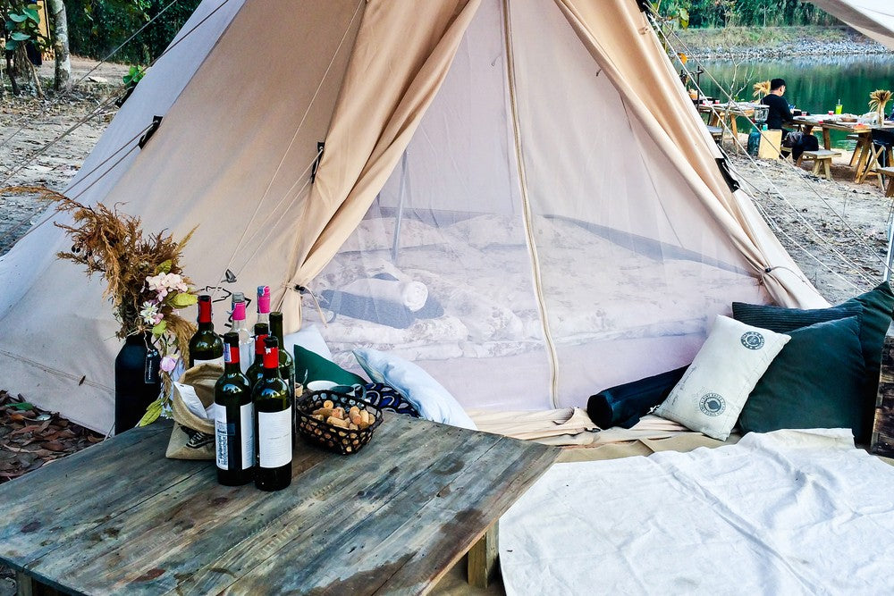 Best wines for camping - red wine bottles rest on a picnic table in front of a tent.