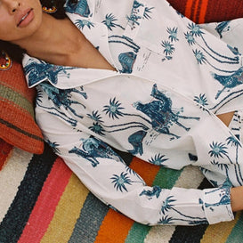 Model laying back on a rainbow stripped blanket in a set of white and blue print pyjamas.