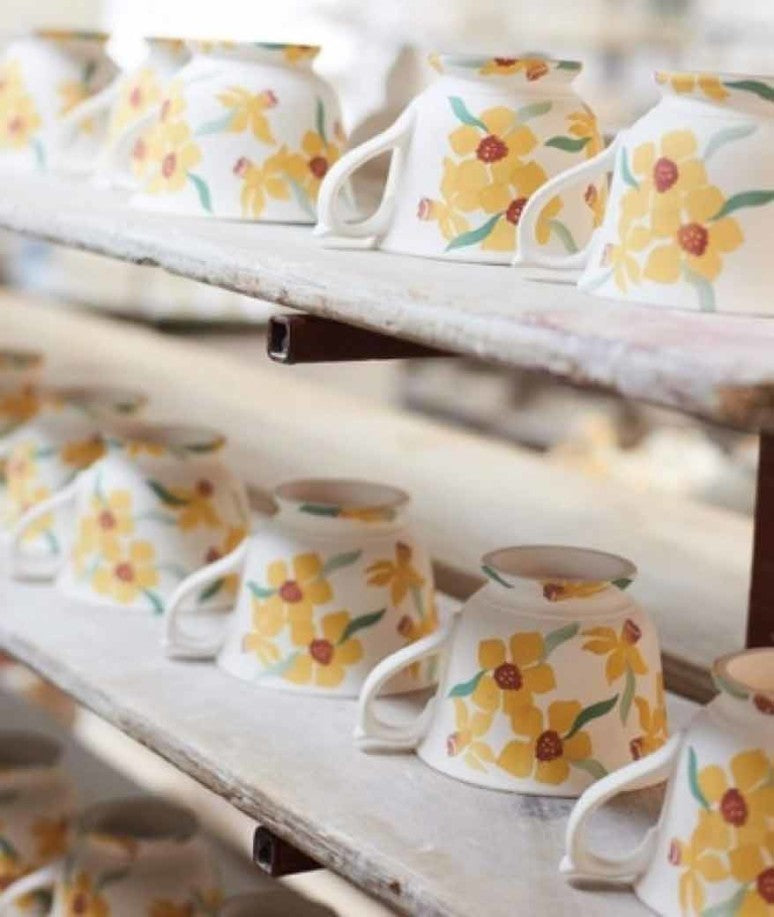 Rows of painted tea mugs are displayed upside down on wooden shelves.