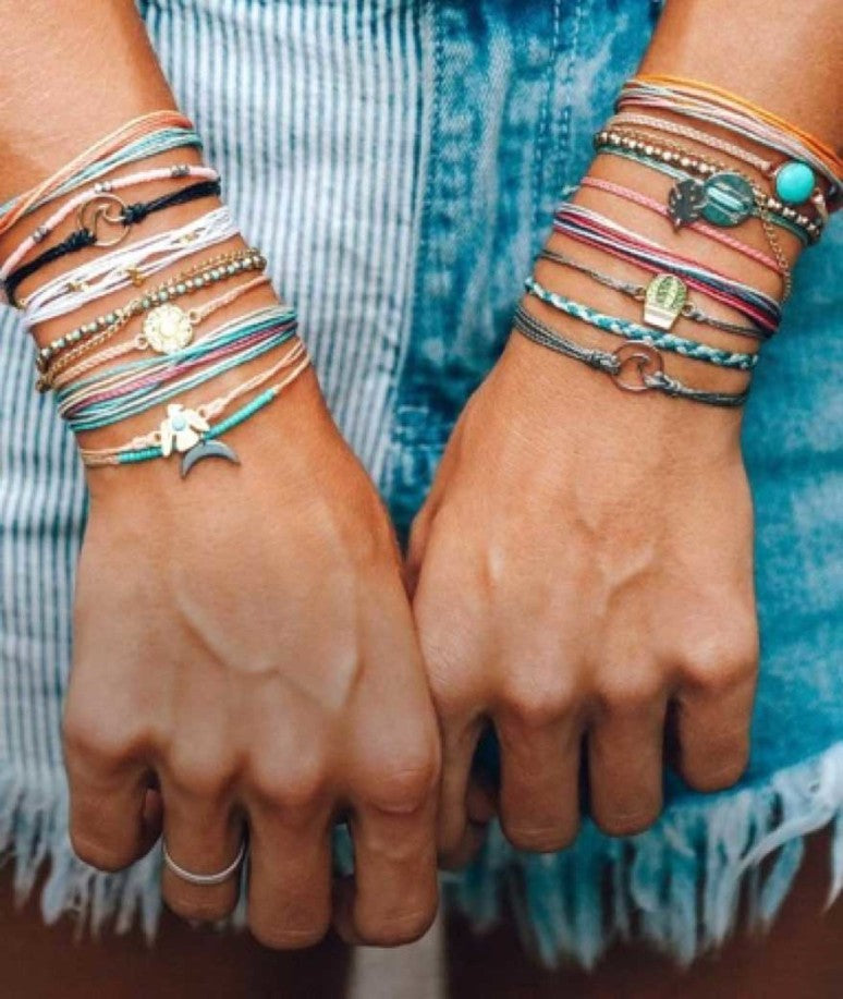 A woman’s arms with several Pura Vida bracelets on each wrist.