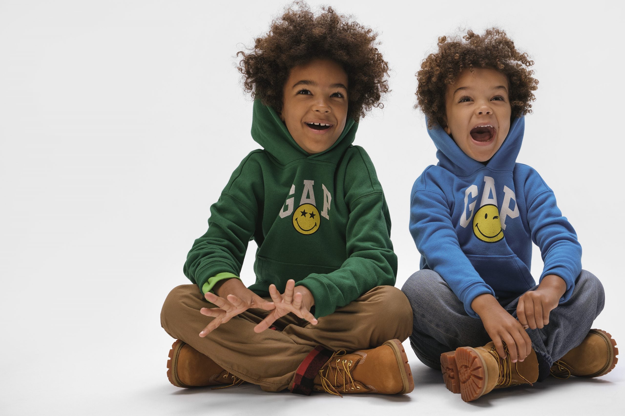 Two kids laughing into the camera whilst wearing hoodies from the Gap x Smiley collaboration.