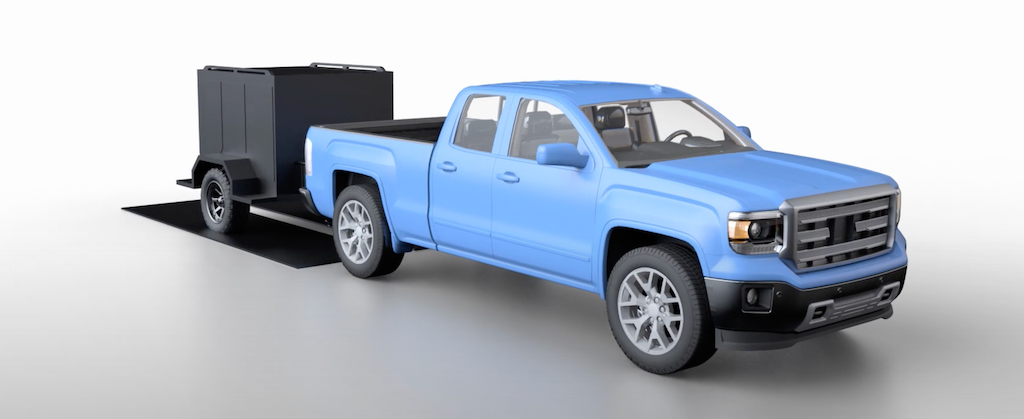 Camion bleu transportant une remorque tout-terrain avec suspension sans essieu