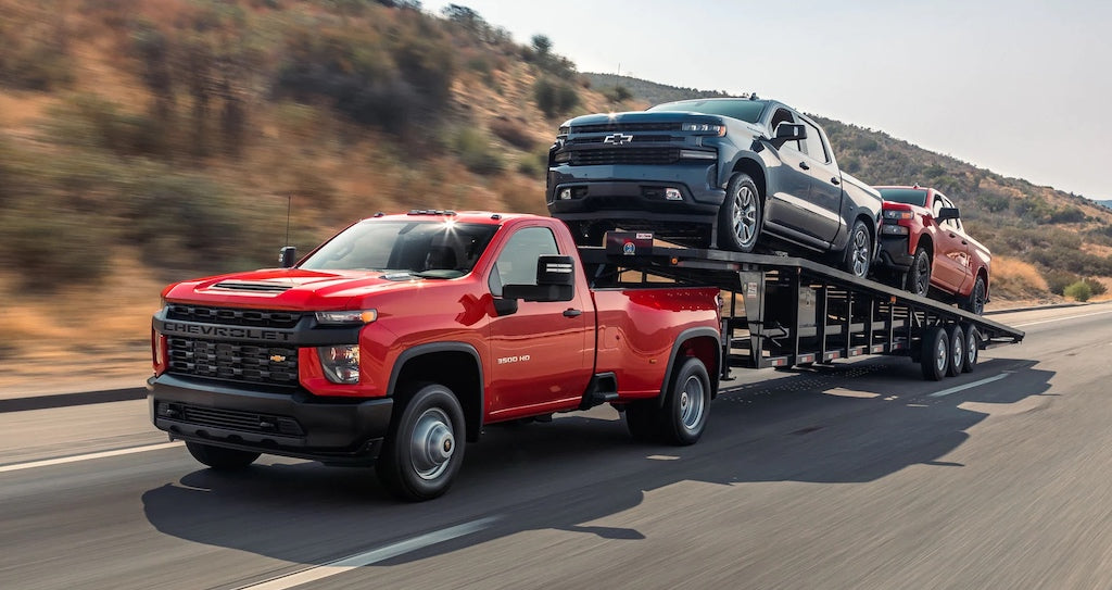 Chevy work truck towing other Chevy trucks