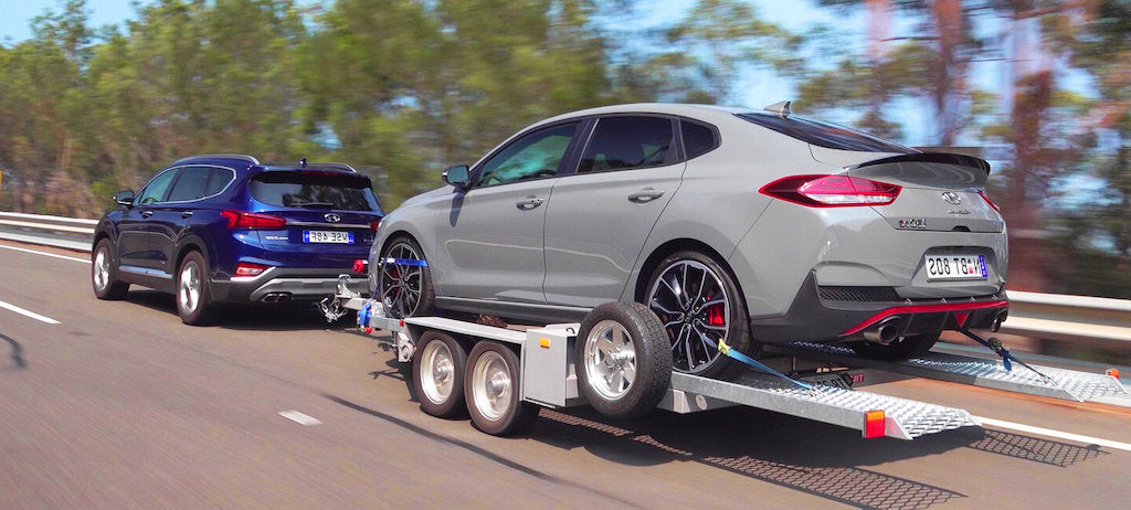 gray car being towed on car trailer