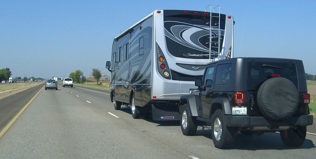 Motor home flat towing a jeep down the highway