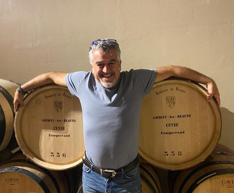 Roberto Cipresso smiling draping his arms over wine barrels