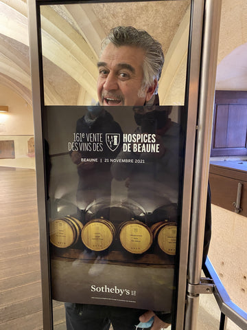 Roberto Cipresso smiling above a flyer advertising the Hospices de Beaune charity wine auction