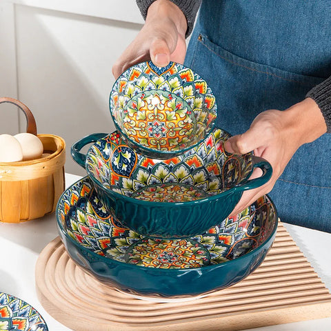 A person holding three ornate bowls stacked on top of each other.