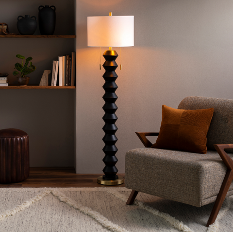 A tall floor lamp with an abstract shape in a dimly lit room