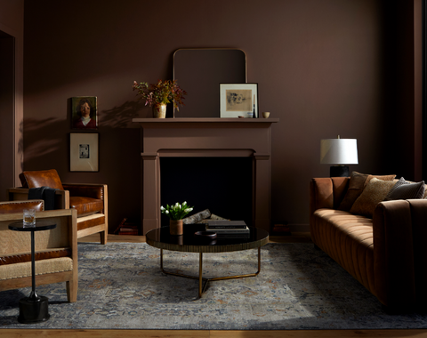 dark moody living room with leather sofa, blue rug and gothic accessories