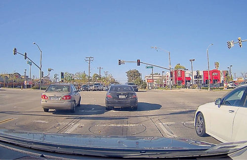 Photo taken from a moving vehicle with the front camera of the d'Action 360. The photo shows the car turning left with several cars in the view as well. 