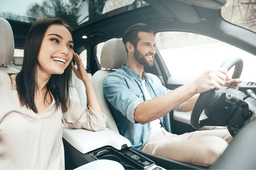 Photo taken inside a vehicle with the 360° camera of the d'Action 360. The photo shows a happy man driving with a happy woman in the passenger's seat. 