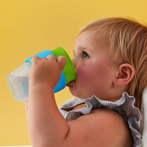 a toddler with a 360 cup against a yellow background