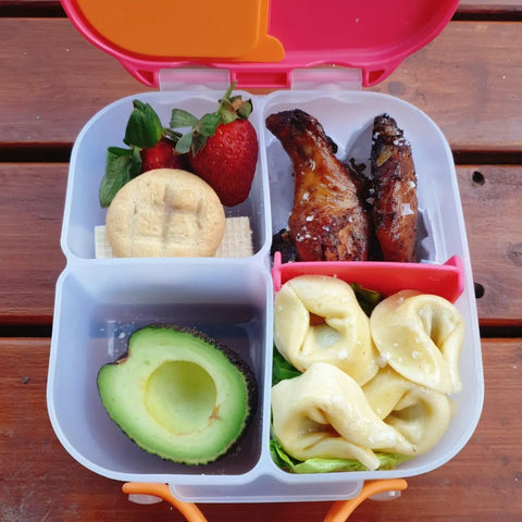 a b.box bento box filled with tortellini noodles, avocado, and chicken wings