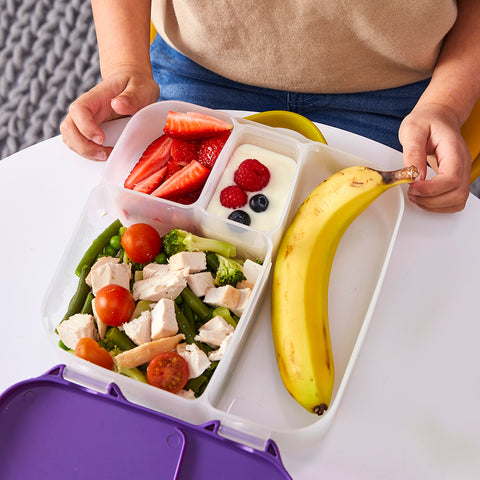 a close up image of a non-toxic bento box filled with chicken, salad, a banana, and yogurt