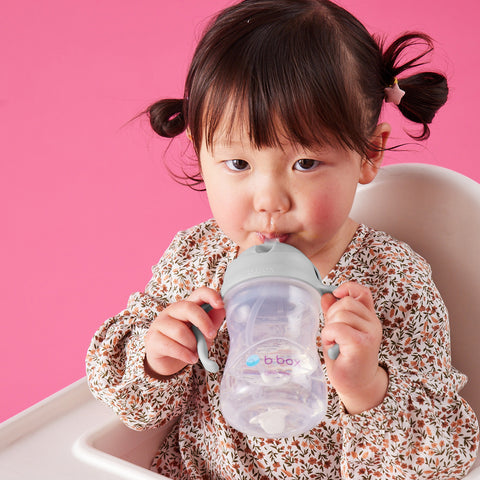 a toddler drinks from a sippy cup