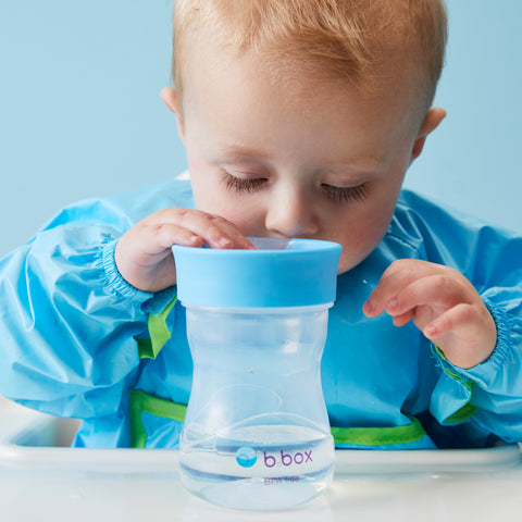 a toddler drinks from a training cup