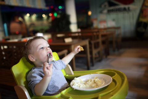 Child has a lunch in a highchair