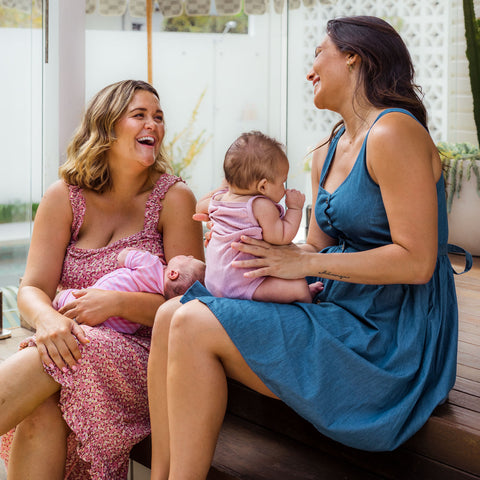 two mums with new babies connecting and laughing fourth trimester breastfeeding