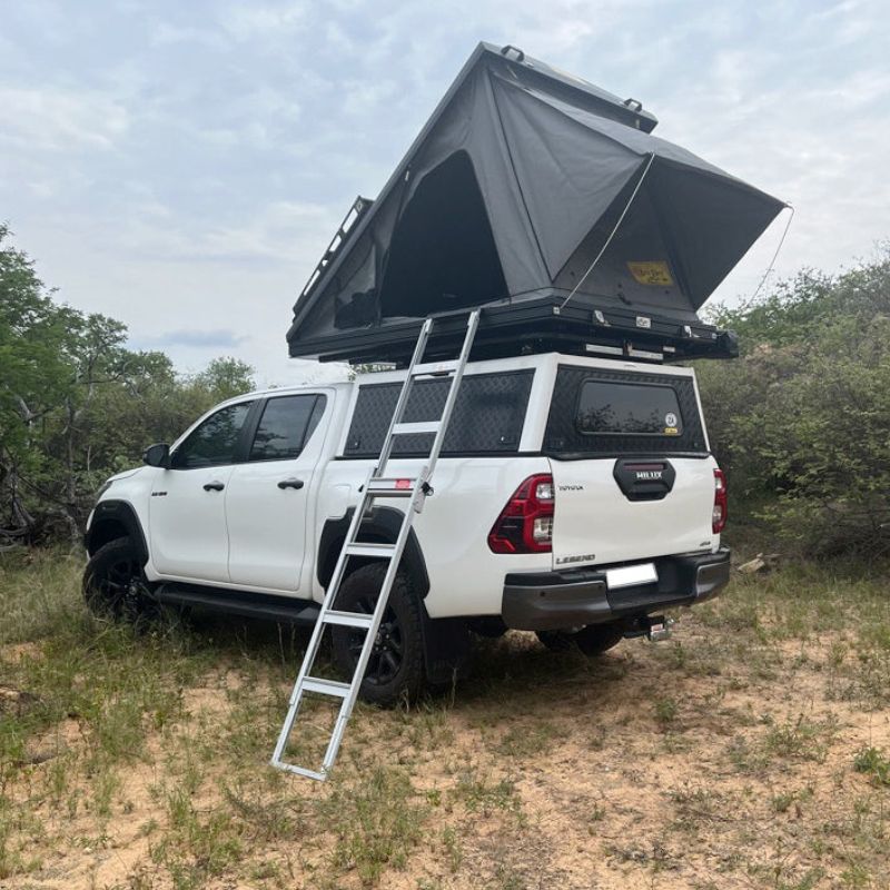 eezi-awn-blade-40th-edition-hard-shell-roof-top-tent-open-rear-corner-view-on-vehicle-with-ladder-in-nature