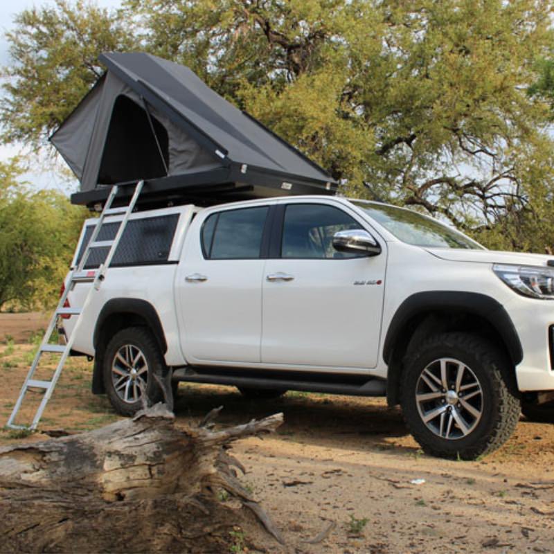 eezi-awn-blade-hard-shell-roof-top-tent-open-front-corner-view-on-vehicle-with-extended-ladder-in-forest