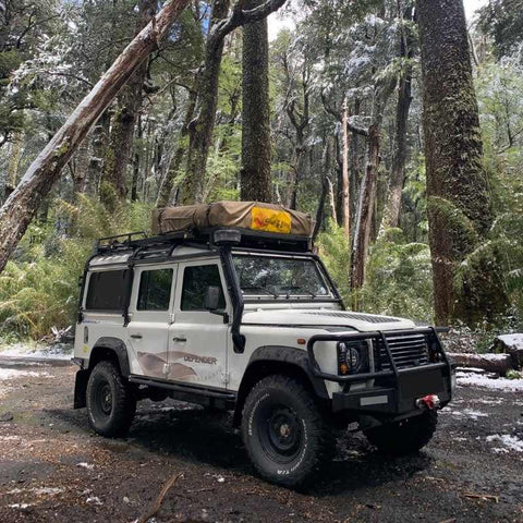 eezi-awn-series-3-soft-shell-roof-top-tent-closed-front-corner-view-on-land-rover-defender-in-forest