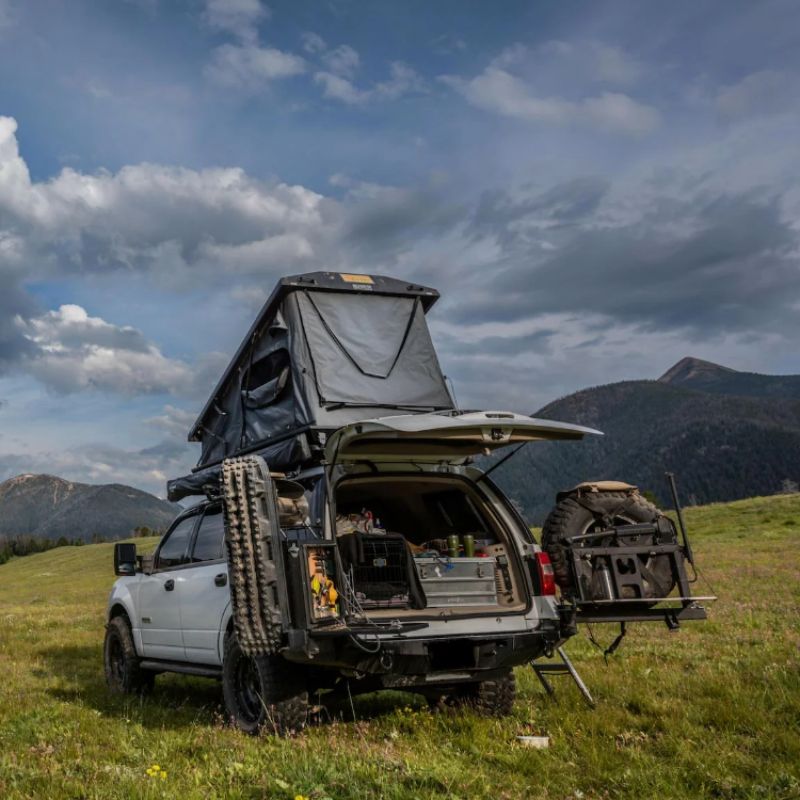 eezi-awn-stealth-hard-shell-roof-top-tent-open-rear-view-on-ford-explorer-in-green-field