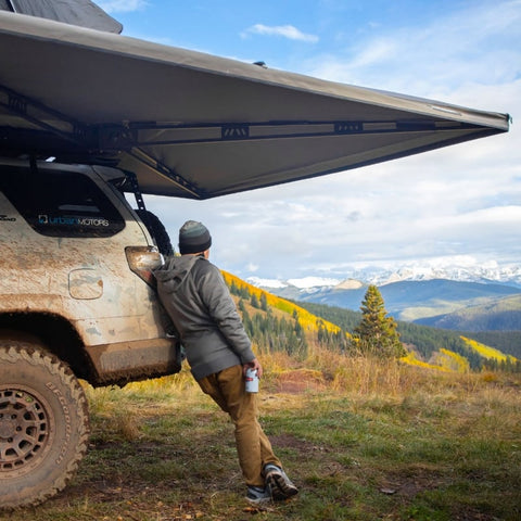 freespirit-recreation-270-awning-driver-side-open-side-view-on-vehicle-in-nature-with-person-facing-away