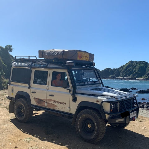 open-road-overland-land-rover-defender-with-eezi-awn-series-3-soft-shell-roof-top-tent-closed-front-corner-view-on-beach