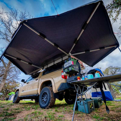 overland-vehicle-systems-nomadic-270-awning-driverside-open-rear-corner-view-on-toyota-tacoma-at-campsite