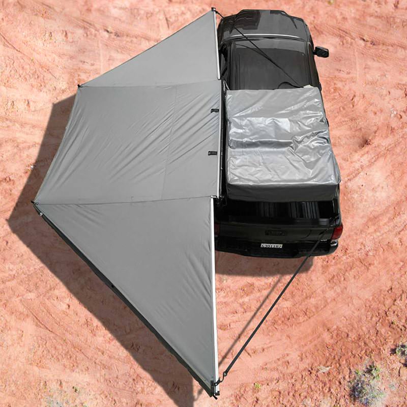 overland-vehicle-systems-nomadic-awning-180-with-bracket-kit-for-mid-high-roofline-vans-driver-side-open-top-view-on-toyota-tacoma-in-desert