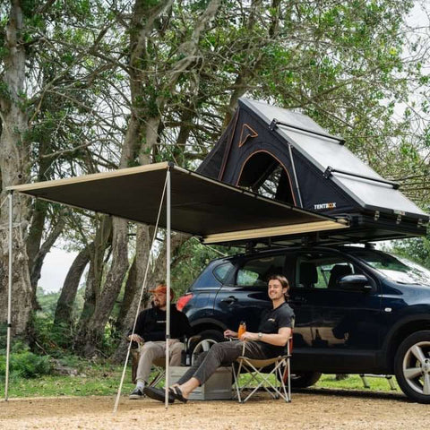 tentbox-cargo-hard-shell-roof-top-tent-open-front-corner-view-on-vehicle-in-forest-with-persons-camping