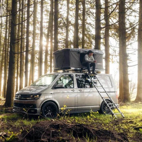 tentbox-classic-hard-shell-roof-top-tent-open-front-corner-view-on-vw-caravelle-in-forest-with-person-camping