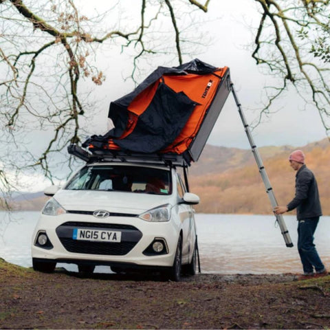 tentbox-lite-1-0-soft-shell-roof-top-tent-orange-side-view-on-hyundai-with-person-packing-up-tent-in-nature