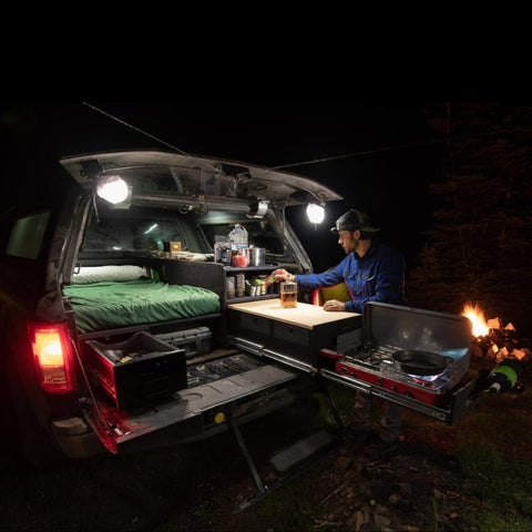 truck-vault-base-camp-5-open-rear-corner-view-installed-in-vehicle-with-person-cooking-in-camp-at-night