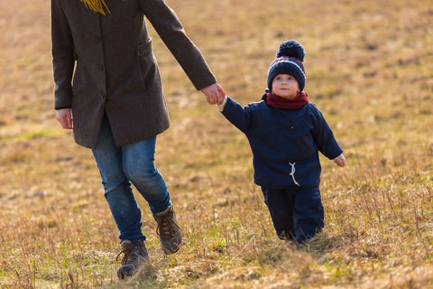 bébé tenant la main de maman dans un champ en hiver