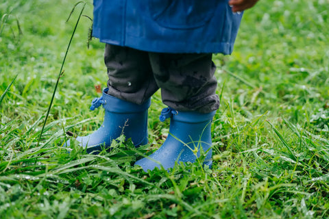 bébé avec des bottes bleues dans l'herbe