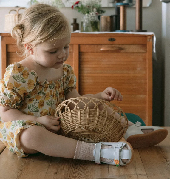 petite fille assise par terre avec un panier et des sandales chaussettes