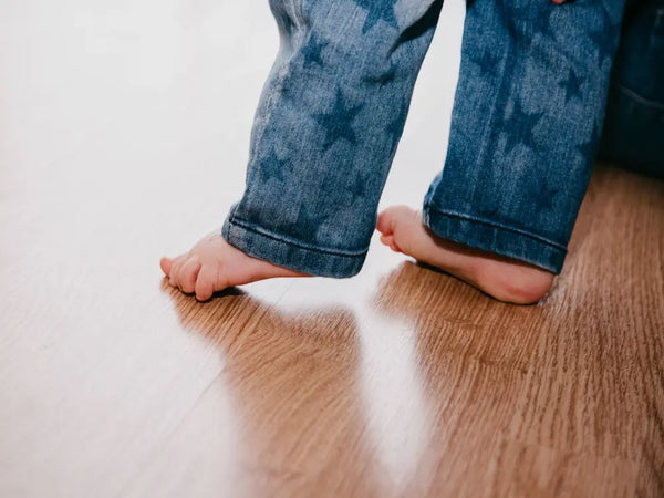 bébé pied nu sur parquet en jean