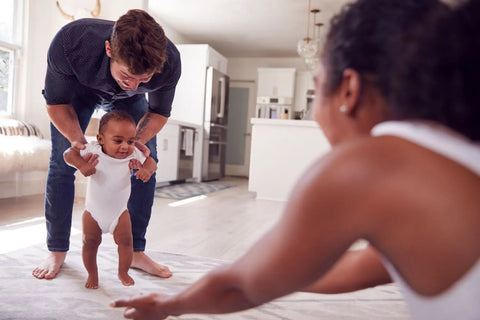 bébé métisse qui apprend à marcher avec papa maman