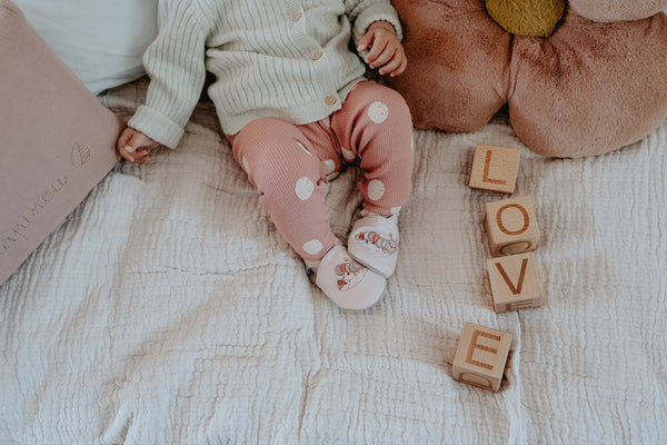 bébé avec chaussons ludiques rose sur un lit Love