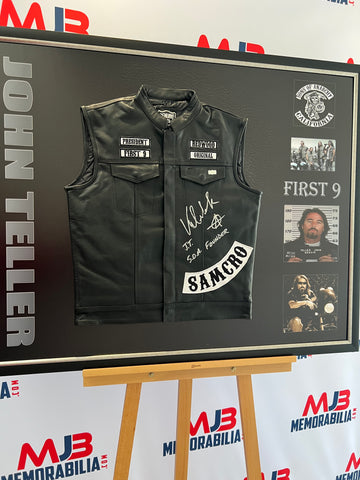 Image: A collection of nine exclusive Sons of Anarchy vests signed by Victor Newmark, who portrayed John Teller on the show. Each vest is adorned with the inscription "JT SOA Founder" and the Sons of Anarchy logo. The vests are showcased on a sleek black backdrop, emphasizing their authenticity and exclusivity