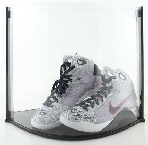 Pair of Nike Hyperdunk basketball shoes signed and inscribed by Kobe Bryant displayed in a custom case, accompanied by an official Panini hologram and Certificate of Authenticity. The size 14 shoes, reminiscent of the athletic prowess of the late basketball legend, currently stand as a sought-after item on auction