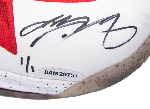 A close-up view of the game-used, signed and inscribed sneakers worn by LeBron James during the 2013 Eastern Conference Finals, highlighting their vibrant colors, design features, and signs of wear against a neutral background