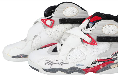 Close-up view of a pair of 1992-93 game-used, twice-signed Air Jordan 8 sneakers from Michael Jordan. The shoes are visibly worn, with signs of age and use, notably the degraded soles. The main highlight is Jordan's signature on each shoe's outstep, written in bold black marker