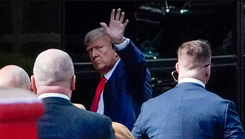 Former US President Donald Trump stepping off a plane in New York City, surrounded by security personnel, as he prepares for his upcoming arraignment