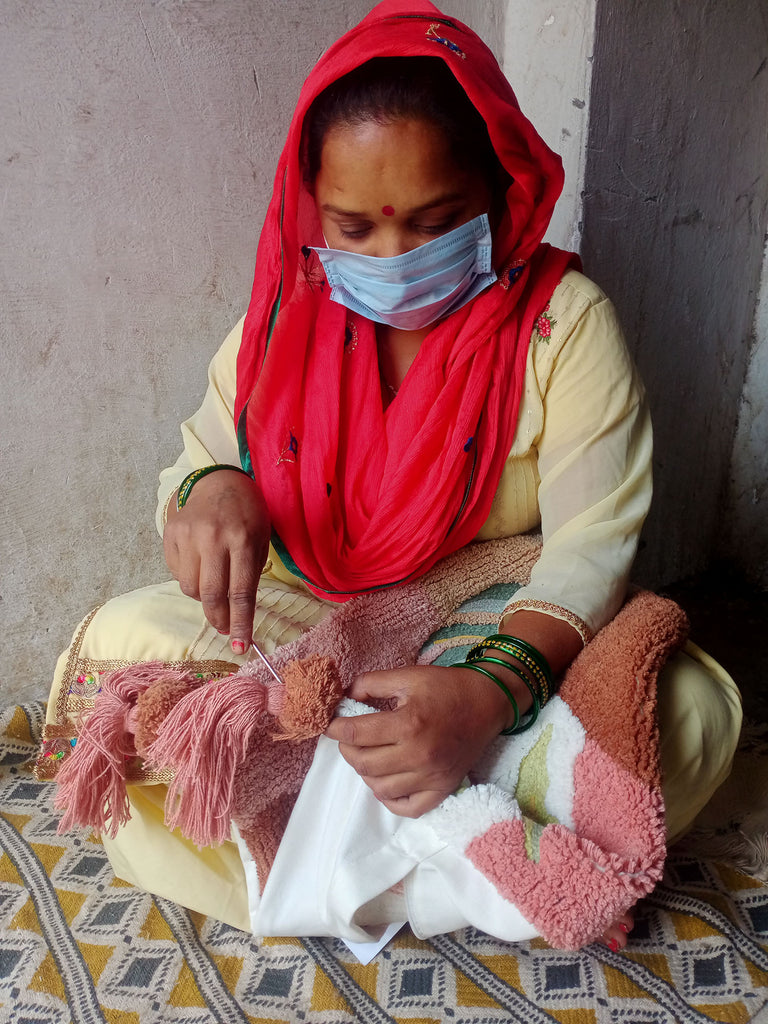 Artisan hand sewing a pom onto pillow