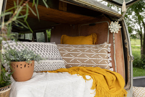 back of camper van layered with pillows, garland and floral wall art in bohemian style