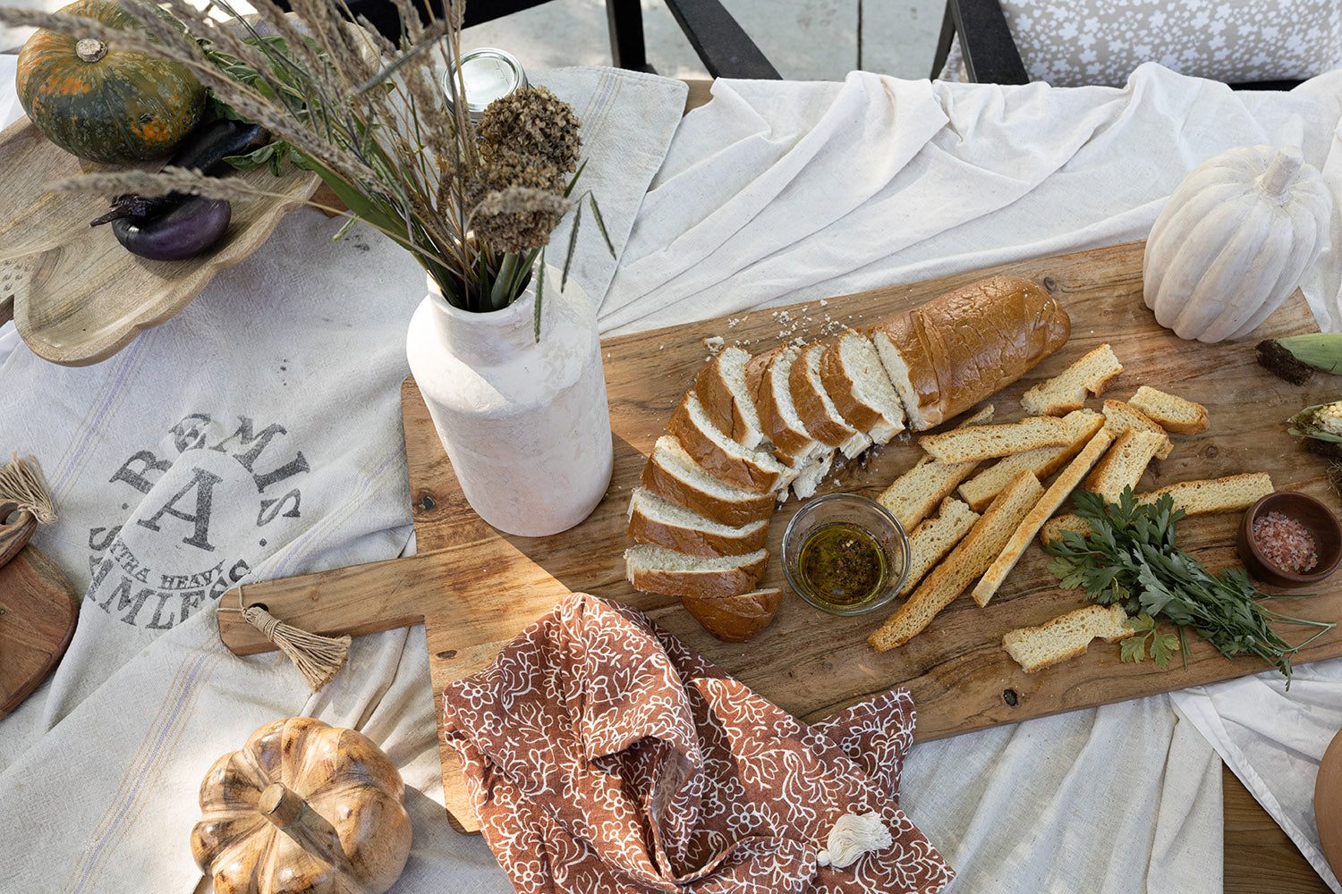 tablecloth covered table with large cutting board with breads and oils