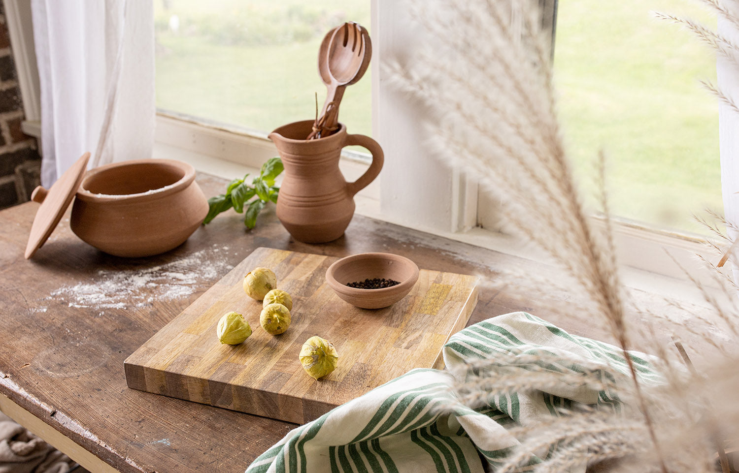 end grain cutting board on table with terracotta pitcher, pot and small bowl